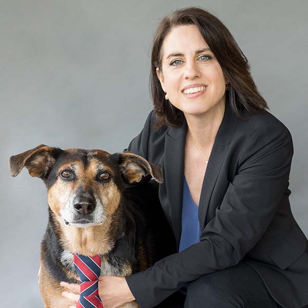 Hospital Director, Carlisa Harris, smiling happily and hugging her pet tan and brown dog