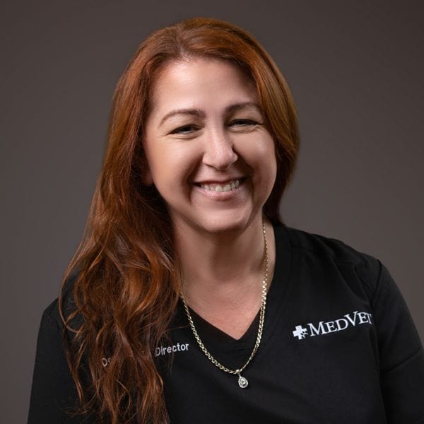 Hospital Director, Dove Butler, smiling happily and wearing black MedVet scrubs.