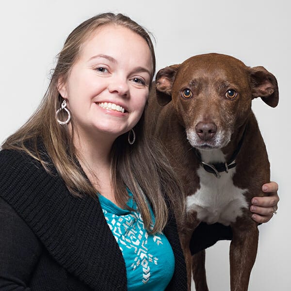 Dr. DeAnna Cotton, Emergency Medicine Veterinarian and Medical Director of MedVet Lexington, smiling while hugging her brown and white dog